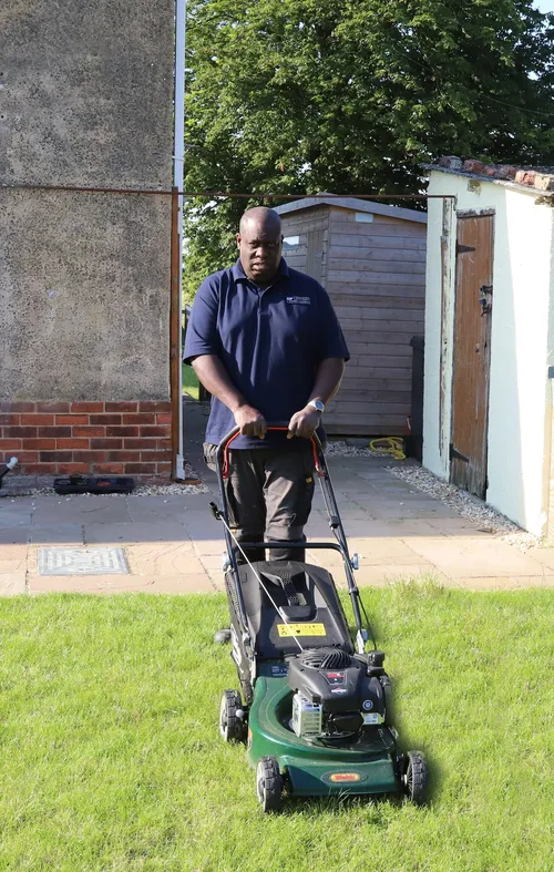 Front view of Andrew Fisher mowing a lawn with a petrol lawn mower